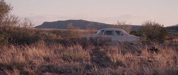 Movie still from “The Killer Inside Me” (2010), directed by Michael Winterbottom – An old car parked in the middle of a grassy field; Extreme Wide shot, High angle