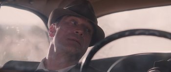 Movie still from “The Killer Inside Me” (2010), directed by Michael Winterbottom – A person wearing a hat driving a car; Close Up shot, Low angle