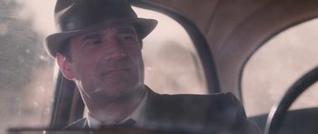 Movie still from “The Killer Inside Me” (2010), directed by Michael Winterbottom – A man wearing a suit and a hat looking out a window; Close Up shot, Low angle