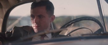 Movie still from “The Killer Inside Me” (2010), directed by Michael Winterbottom – A man sitting in the back seat of a car looking out of the window; Close Up shot, Low angle