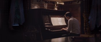 Movie still from “The Killer Inside Me” (2010), directed by Michael Winterbottom – A man sitting in front of an old style piano; Medium shot, High angle