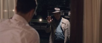 Movie still from “The Killer Inside Me” (2010), directed by Michael Winterbottom – A man in a hat and a jacket standing in front of a mirror; Medium shot, Over the shoulder angle