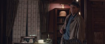 Movie still from “The Killer Inside Me” (2010), directed by Michael Winterbottom – An older man wearing a hat and a coat; Medium shot, Over the shoulder angle