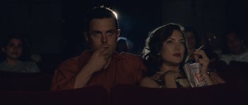 Movie still from “The Killer Inside Me” (2010), directed by Michael Winterbottom – A man and a woman sitting next to each other in a movie theater; Medium shot, Low angle