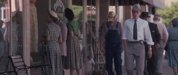 Movie still from “The Killer Inside Me” (2010), directed by Michael Winterbottom – A group of people standing in front of a building; Medium shot, Over the shoulder angle