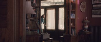 Movie still from “The Killer Inside Me” (2010), directed by Michael Winterbottom – A woman standing in front of a window in a room; Wide shot, Low angle