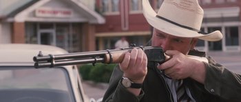 Movie still from “The Killer Inside Me” (2010), directed by Michael Winterbottom – A man in a cowboy hat is holding a rifle; Close Up shot, Over the shoulder angle