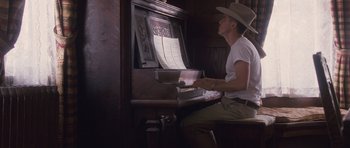 Movie still from “The Killer Inside Me” (2010), directed by Michael Winterbottom – A man in a cowboy hat playing a piano; Medium shot, Low angle