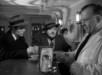 Movie still from “The Killers” (1946), directed by Robert Siodmak – A group of men sitting at a table in a restaurant; Medium shot, Over the shoulder angle