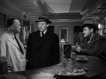 Movie still from “The Killers” (1946), directed by Robert Siodmak – A group of men standing next to each other in front of a bar; Medium shot, Over the shoulder angle