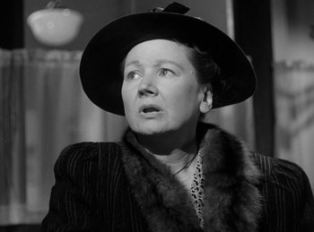 Movie still from “The Killers” (1946), directed by Robert Siodmak – An older woman wearing a black hat and a fur collar; Close Up shot, Low angle