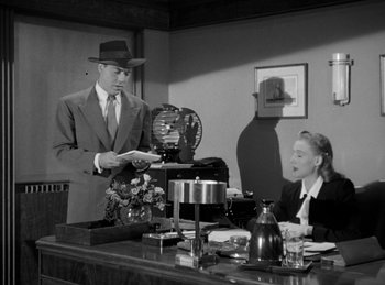 Movie still from “The Killers” (1946), directed by Robert Siodmak – A man in a suit and a woman in a dress suit; Medium shot, Low angle