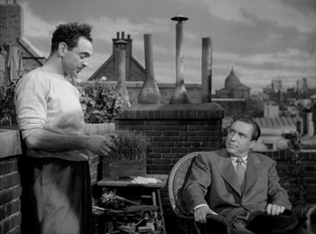 Movie still from “The Killers” (1946), directed by Robert Siodmak – Two men sitting on a chair in front of a building; Medium shot, Low angle