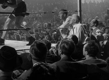 Movie still from “The Killers” (1946), directed by Robert Siodmak – A crowd of people in a boxing ring watching an event; Wide shot, High angle