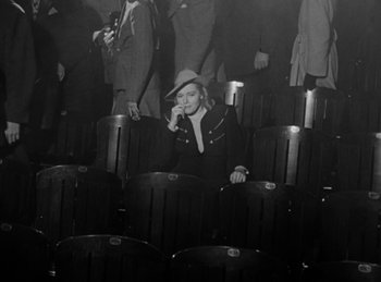 Movie still from “The Killers” (1946), directed by Robert Siodmak – A woman sitting in an audience wearing a hat; Wide shot, High angle