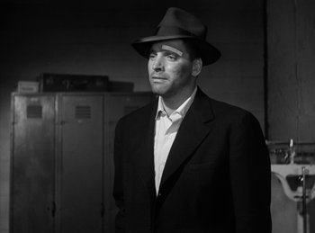Movie still from “The Killers” (1946), directed by Robert Siodmak – A black and white photo of a man in a suit and hat; Close Up shot, Low angle