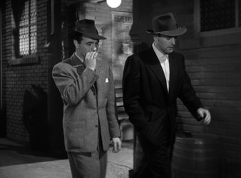 Movie still from “The Killers” (1946), directed by Robert Siodmak – Two men walking down the street in suits and hats; Medium shot, Low angle