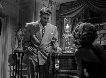 Movie still from “The Killers” (1946), directed by Robert Siodmak – A man and a woman are standing in front of a chair; Medium shot, Low angle