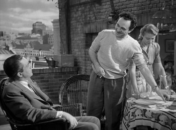 Movie still from “The Killers” (1946), directed by Robert Siodmak – A man standing next to two women on a balcony; Medium shot, Over the shoulder angle