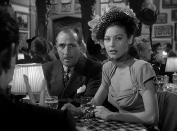 Movie still from “The Killers” (1946), directed by Robert Siodmak – A man and a woman sitting at a table with wine glasses in front of them; Medium shot, Over the shoulder angle