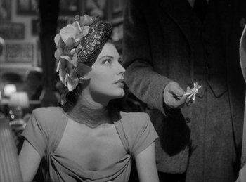 Movie still from “The Killers” (1946), directed by Robert Siodmak – An old photo of a woman in a hat with a cigarette in her mouth; Close Up shot, Over the shoulder angle