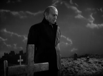 Movie still from “The Killers” (1946), directed by Robert Siodmak – A man standing in front of a cross in a cemetery; Medium shot, Low angle