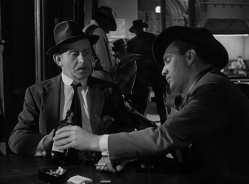 Movie still from “The Killers” (1946), directed by Robert Siodmak – Two men sitting at a table talking to each other; Close Up shot, Over the shoulder angle