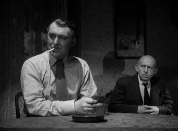 Movie still from “The Killers” (1946), directed by Robert Siodmak – Two men sitting at a table smoking a cigarette; Medium shot, High angle