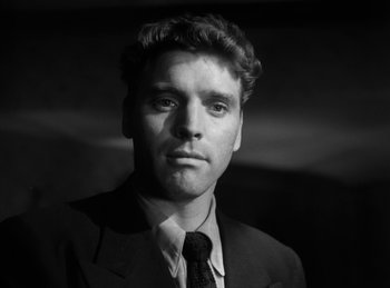 Movie still from “The Killers” (1946), directed by Robert Siodmak – Black and white photograph of a man wearing a suit and tie; Close Up shot, Low angle