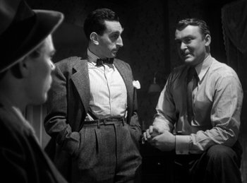 Movie still from “The Killers” (1946), directed by Robert Siodmak – A black - and - white photo of two men talking to another man; Medium shot, Low angle