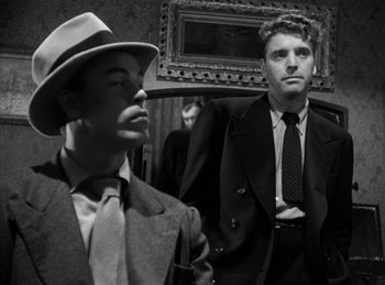 Movie still from “The Killers” (1946), directed by Robert Siodmak – A man in a suit and a man in a hat and tie; Medium shot, Low angle