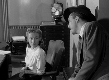 Movie still from “The Killers” (1946), directed by Robert Siodmak – A man and a woman sitting next to each other in a room; Medium shot, Over the shoulder angle