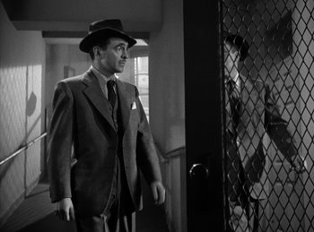 Movie still from “The Killers” (1946), directed by Robert Siodmak – A man in a suit and hat walking in front of an open door; Medium shot, Over the shoulder angle