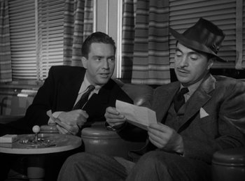 Movie still from “The Killers” (1946), directed by Robert Siodmak – Two men sitting on a couch looking at a piece of paper; Medium shot, Low angle
