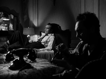 Movie still from “The Killers” (1946), directed by Robert Siodmak – A man sitting in front of another man in a chair; Medium shot, High angle