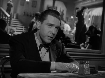 Movie still from “The Killers” (1946), directed by Robert Siodmak – A black and white photo of a man sitting at a table; Close Up shot, Low angle