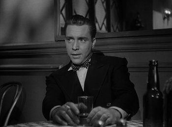Movie still from “The Killers” (1946), directed by Robert Siodmak – A man sitting at a table with a glass of wine; Close Up shot, Low angle