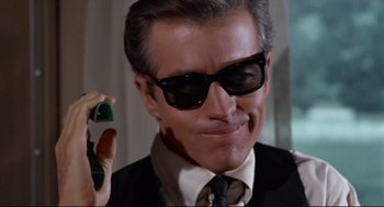 Movie still from “The Killers” (1964), directed by Don Siegel – A person wearing sunglasses and holding a cell phone; Close Up shot, Low angle