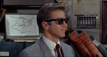 Movie still from “The Killers” (1964), directed by Don Siegel – A person wearing a suit and sunglasses; Close Up shot, Low angle