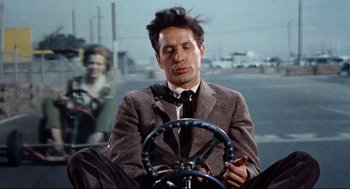 Movie still from “The Killers” (1964), directed by Don Siegel – A man sitting in the drivers seat of a car; Medium shot, Low angle