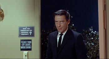 Movie still from “The Killers” (1964), directed by Don Siegel – A man in a suit and tie standing in front of a building; Medium shot, Low angle