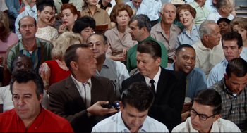 Movie still from “The Killers” (1964), directed by Don Siegel – A crowd of people sitting in a room; Medium shot, High angle