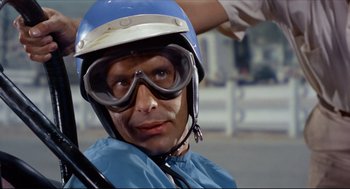 Movie still from “The Killers” (1964), directed by Don Siegel – A man wearing goggles and a helmet on a motorcycle; Close Up shot, Low angle