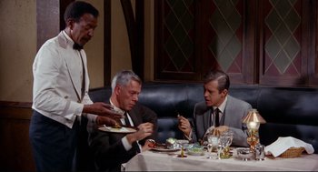 Movie still from “The Killers” (1964), directed by Don Siegel – A group of men sitting at a table with plates of food in front of them; Medium shot, High angle