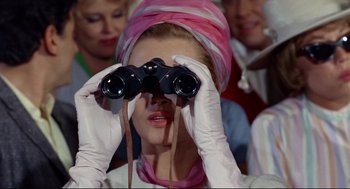 Movie still from “The Killers” (1964), directed by Don Siegel – A woman wearing white gloves looking through binoculars; Close Up shot, Low angle