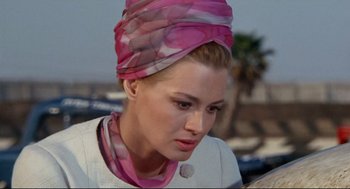 Movie still from “The Killers” (1964), directed by Don Siegel – A woman wearing a head scarf and a white jacket; Close Up shot, Low angle