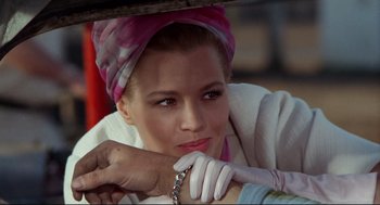 Movie still from “The Killers” (1964), directed by Don Siegel – A woman with a head scarf and gloves holding a metal chain; Close Up shot, Over the shoulder angle