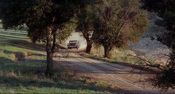 Movie still from “The Killers” (1964), directed by Don Siegel – A truck driving down a dirt road near trees; Extreme Wide shot, High angle