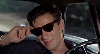 Movie still from “The Killers” (1964), directed by Don Siegel – A person wearing sunglasses in a car; Close Up shot, High angle
