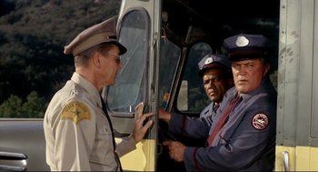 Movie still from “The Killers” (1964), directed by Don Siegel – A group of men standing next to each other in a vehicle; Medium shot, Low angle